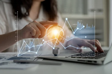 Iconic image: hand typing on laptop, with lines and a light bulb above it to symbolise a BI idea.