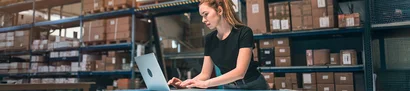 Mitarbeiterin in der Logistik arbeitet mit ERP-System am Laptop zur Lagerbestandsverwaltung.