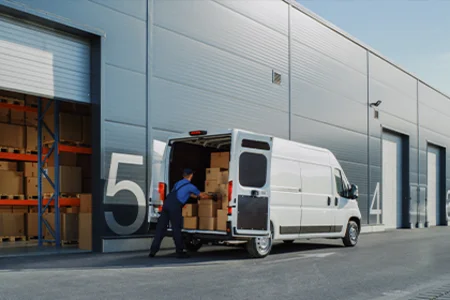Employee loads boxes into a delivery van at the loading bay for online and mail order businesses.