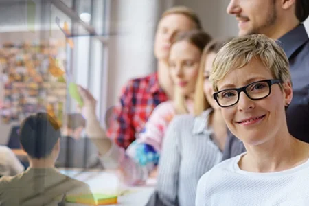 Seminarraum: Personen arbeiten, blonde Seminarleiterin im Vordergrund.