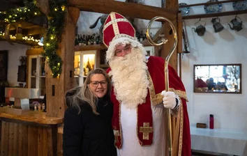 GOB-Mitarbeiterin steht lächelnd neben dem Nikolaus auf dem Weihnachtsevent 2025 im Mengelshof.