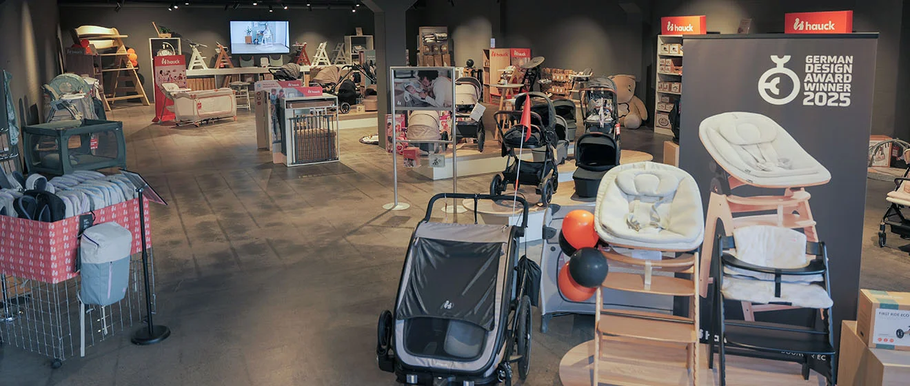Kinderwagen und Hochstühle im hauck-Sortiment Hochstühle und Kinderwagen in der hauck-Produktausstellung mit Banner zum German Design Award 2025.