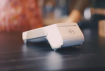 Close-up of a mobile payment terminal with NFC symbol on a dark counter