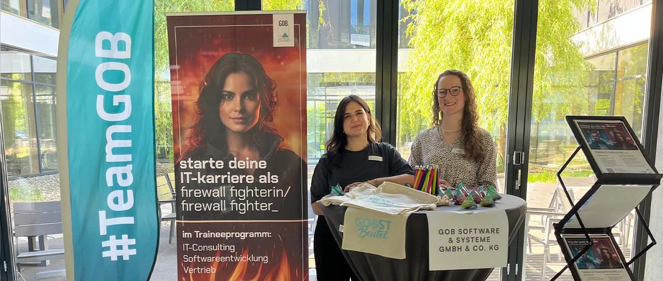 GOB-Stand: Zwei GOB-Recruiting-Kolleginnen stehen am Infotisch, #TeamGOB-Flagge und Karriereplakat.