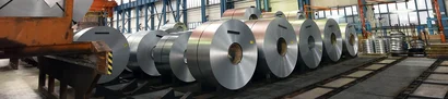 ERP-supported management of steel coils | unitop Large steel coils are lined up in a production hall with crane system and storage areas.
