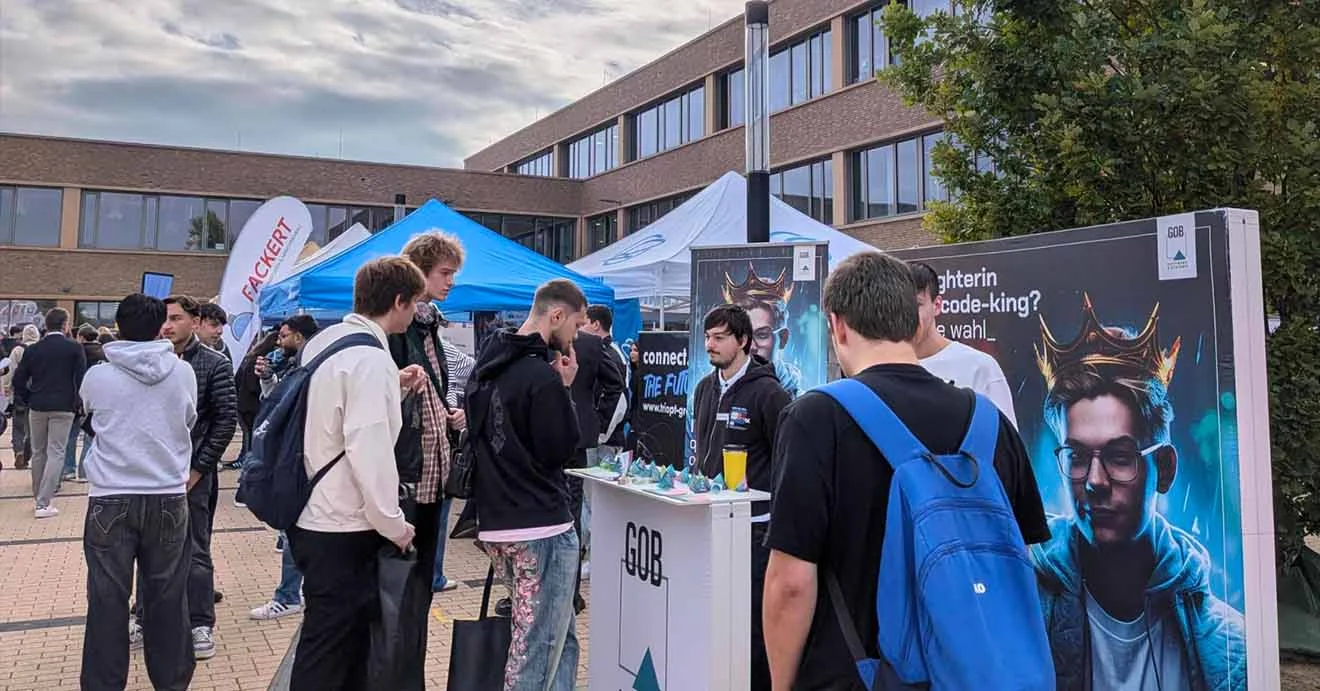 Besucherinnen und Besucher sprechen mit einem GOB-Teammitglied am Messestand.
