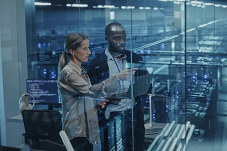 Iconic image: Two people with laptop  doing an AI consultation in front of server racks behind glass