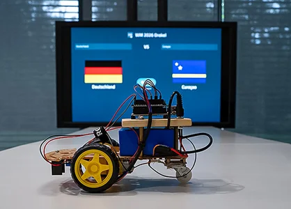 Arduino-Roboter steht vor einem Bildschirm mit dem WM-Orakel 2026.