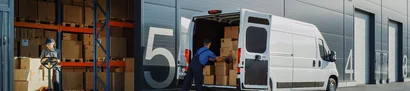 Employee loads boxes into a delivery van at the loading bay for online and mail order businesses.