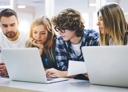 Gemeinsam lernen und wachsen im GOB-Traineeprogramm Vier Personen sitzen an einem Tisch mit zwei Laptops und schauen gemeinsam auf einen Bildschirm.