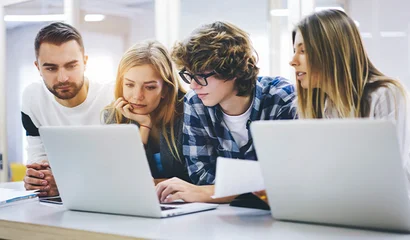 Gemeinsam lernen und wachsen im GOB-Traineeprogramm Vier Personen sitzen an einem Tisch mit zwei Laptops und schauen gemeinsam auf einen Bildschirm.