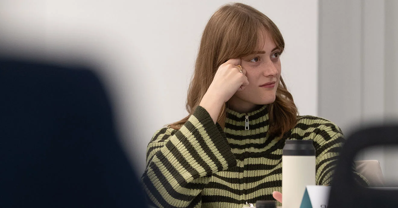 Erste Einblicke ins Traineeprogramm für zukünftige IT-Consultants Ein Trainee im IT-Consulting sitzt an einem Tisch, eine Hand an der Schläfe.