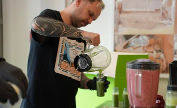 Tätowierter Kellner füllt grünen Smoothie bei der RUB Karrieremesse 2025 in einen Trinkbecher ab