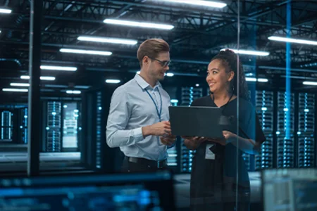 Illustrative image: Two consultants with laptop by server racks for GOB digitalisation consultancy.
