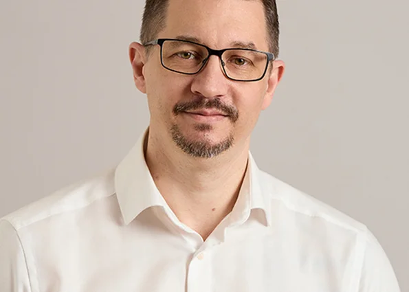 Marcus Hennig – IT-Leiter beim ACV Porträt eines dunkelhaarigen Mannes mit Brille im weißen Hemd vor neutralem Hintergrund.