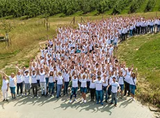 Das Team GOB stellt sich vor Team GOB in weißen T-Shirts versammelt in grüner Landschaft und fröhlich in die Kamera winkend