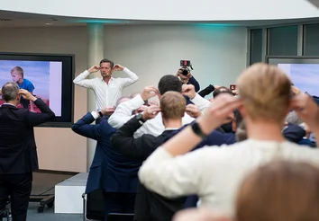 Guus Krabbenborg leitet Übung; Publikum macht mit, Hände am Kopf, Fotograf im Hintergrund.