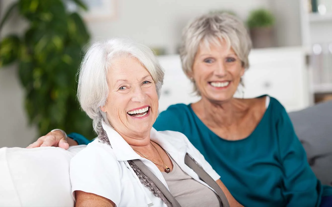 Glückliche ältere Frauen im Rentenalter Zwei ältere Frauen lachen gemeinsam auf dem Sofa und genießen ihren sorgenfreien Ruhestand