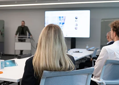 Neue GOB-Trainees sitzen im Schulungsraum und hören bei der IT-Geräte-Ausgabe zu.