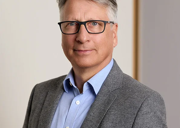 Holger Küster – Geschäftsführer vom ACV Porträt eines Mannes mit Brille im grauen Sakko vor hellem Hintergrund.