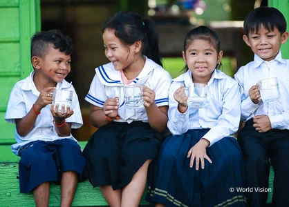 Echtstart bei World Vision Deutschland e. V. | unitop Fundraising | 1920 x 780 Pixel Vier lachende Kinder auf grüner Holztreppe mit Wasser in der Hand, links ein Wasserbehälter.