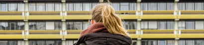 Auf dem Weg zur stellenwerk-Jobmesse 2024 in Bochum Dunkelblonde Studentin mit Rucksack vor RUB-Gebäude, von hinten aufgenommen